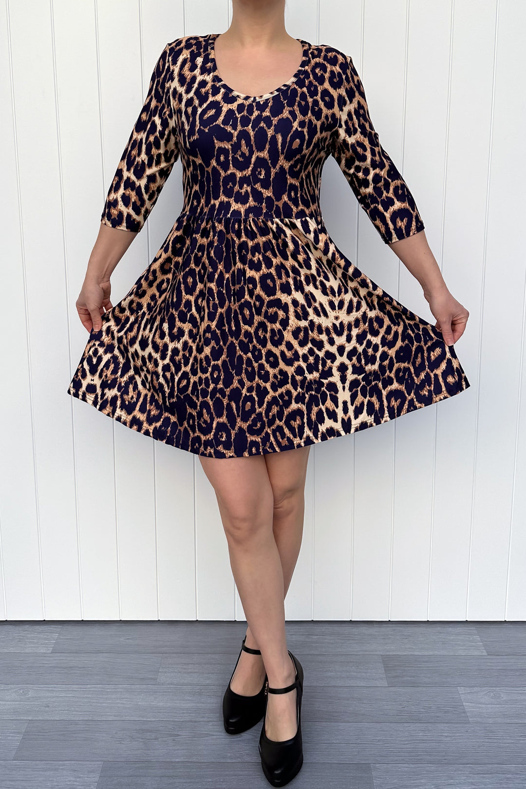 Person wearing a leopard print dress with a white wooden background