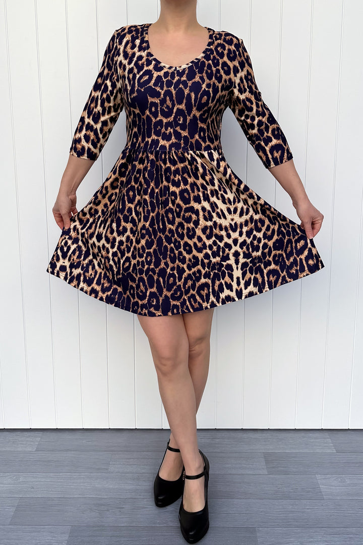 Person wearing a leopard print dress with a white wooden background