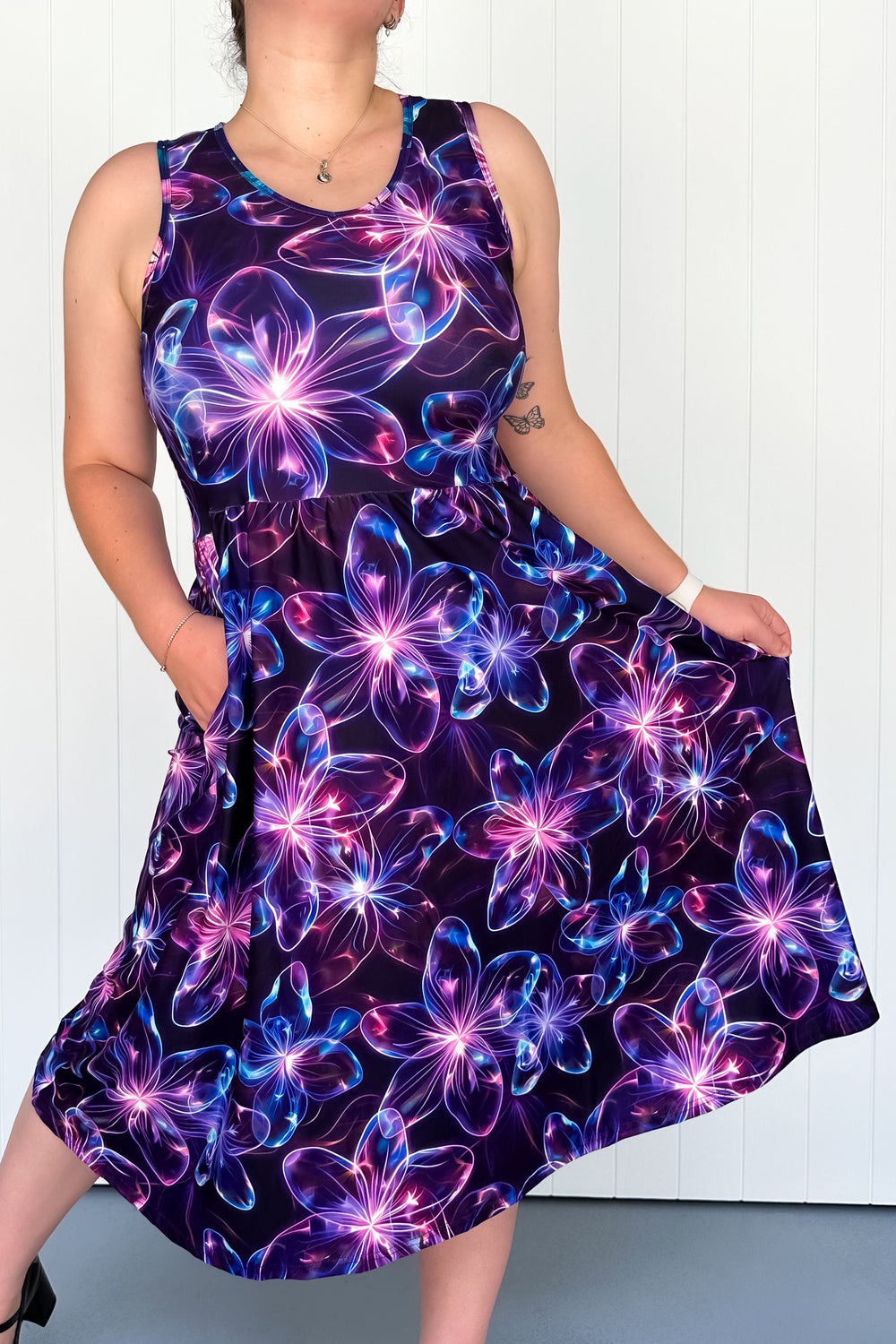 A sleeveless midi dress with a floral pattern in vibrant colors on a diaphanous background, featuring deep side pockets.