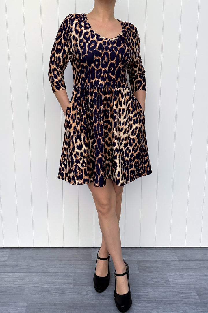Person wearing a leopard print dress against a white wooden panel background