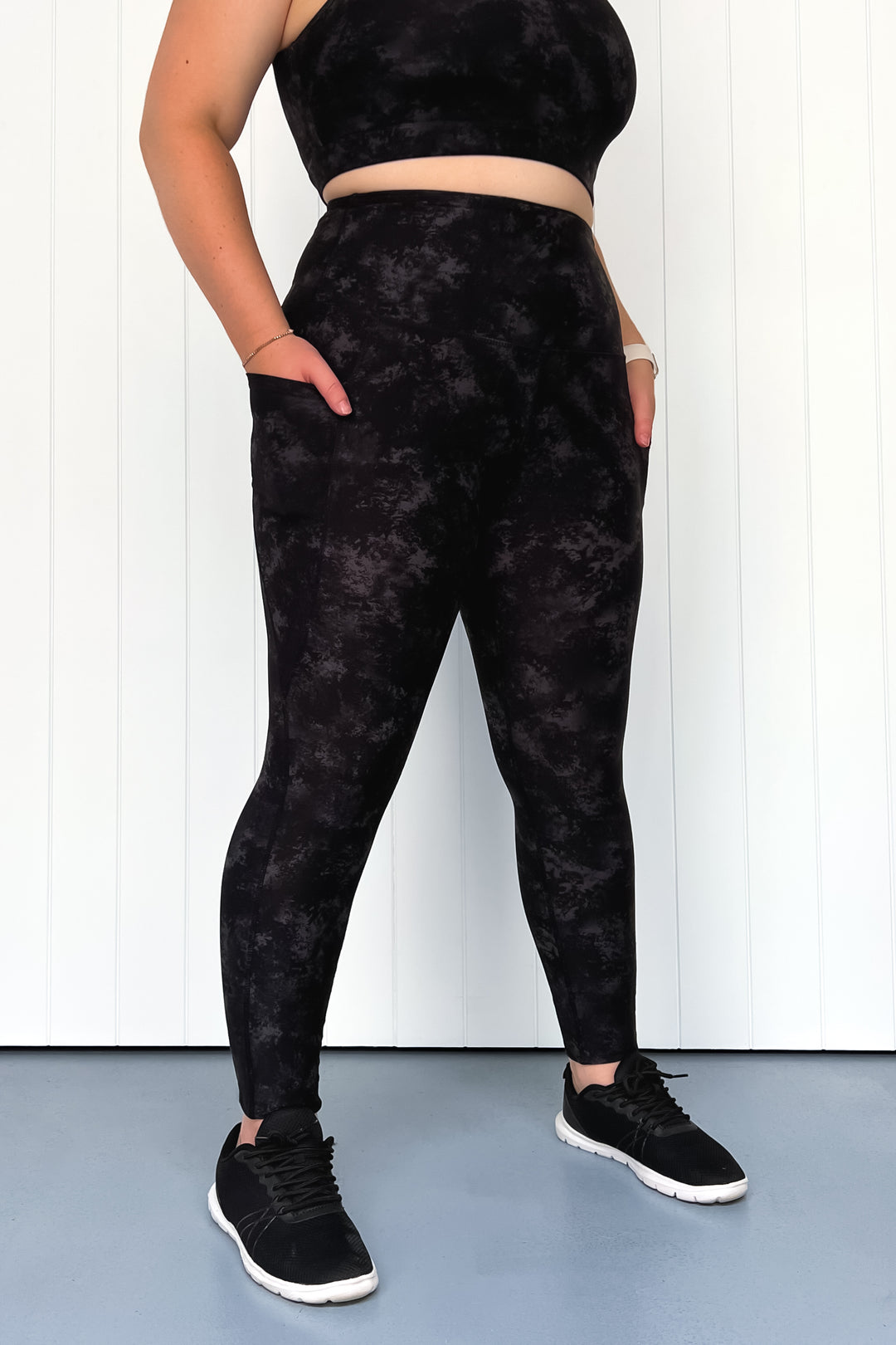 Person wearing black tie-dye leggings and top against a white background