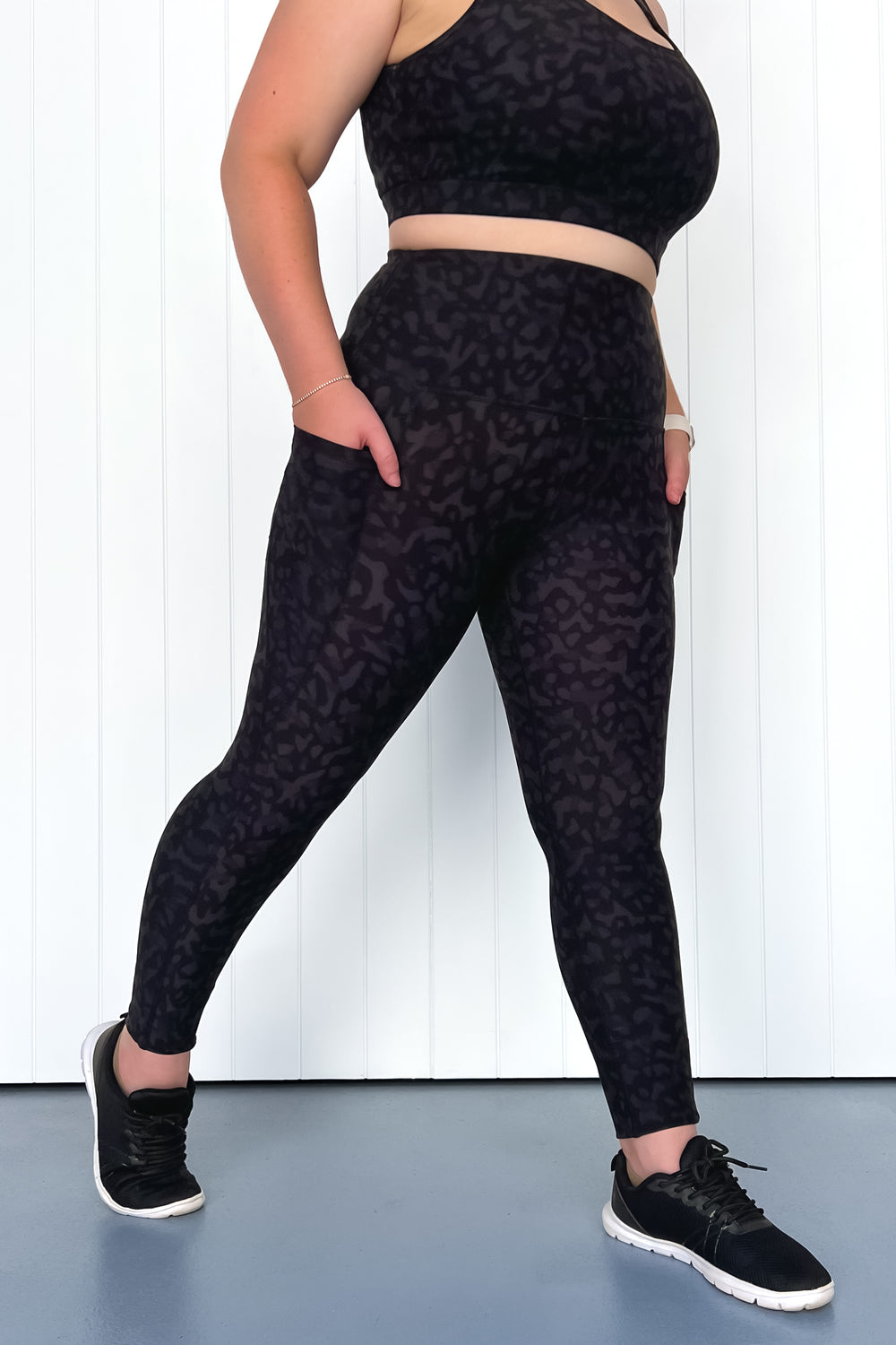 Person wearing black patterned leggings and crop top against a white background