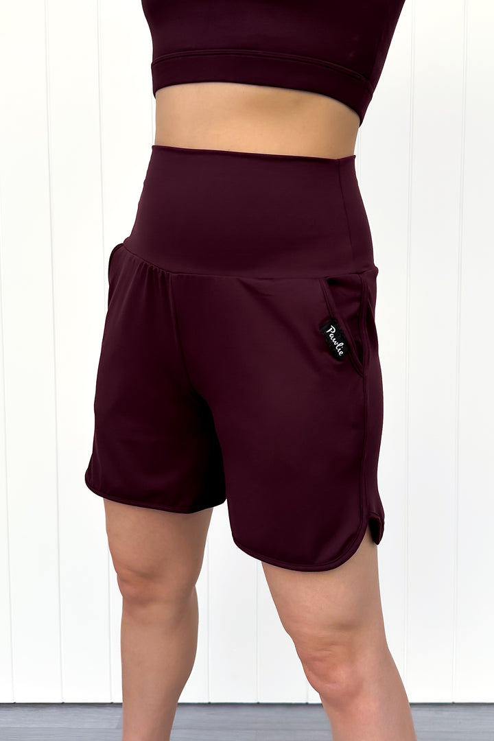 Maroon athletic shorts with a logo on a white background