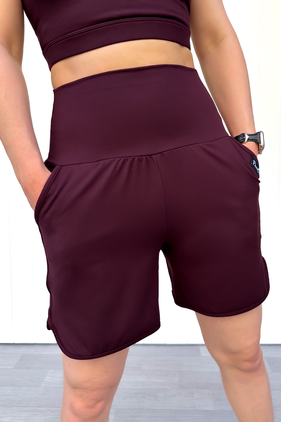Person wearing maroon athletic shorts and top on a plain background