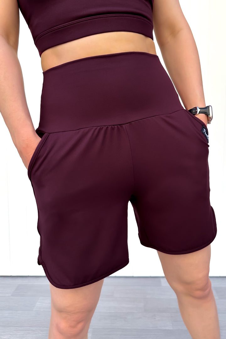 Person wearing maroon athletic shorts and top on a plain background