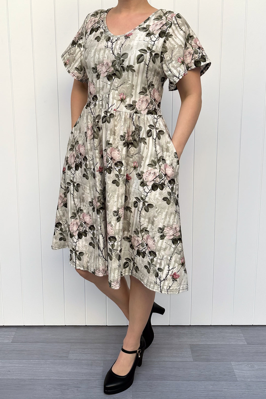 Woman wearing a floral dress against a white wooden panel background