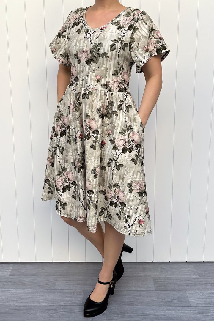 Woman wearing a floral dress against a white wooden panel background