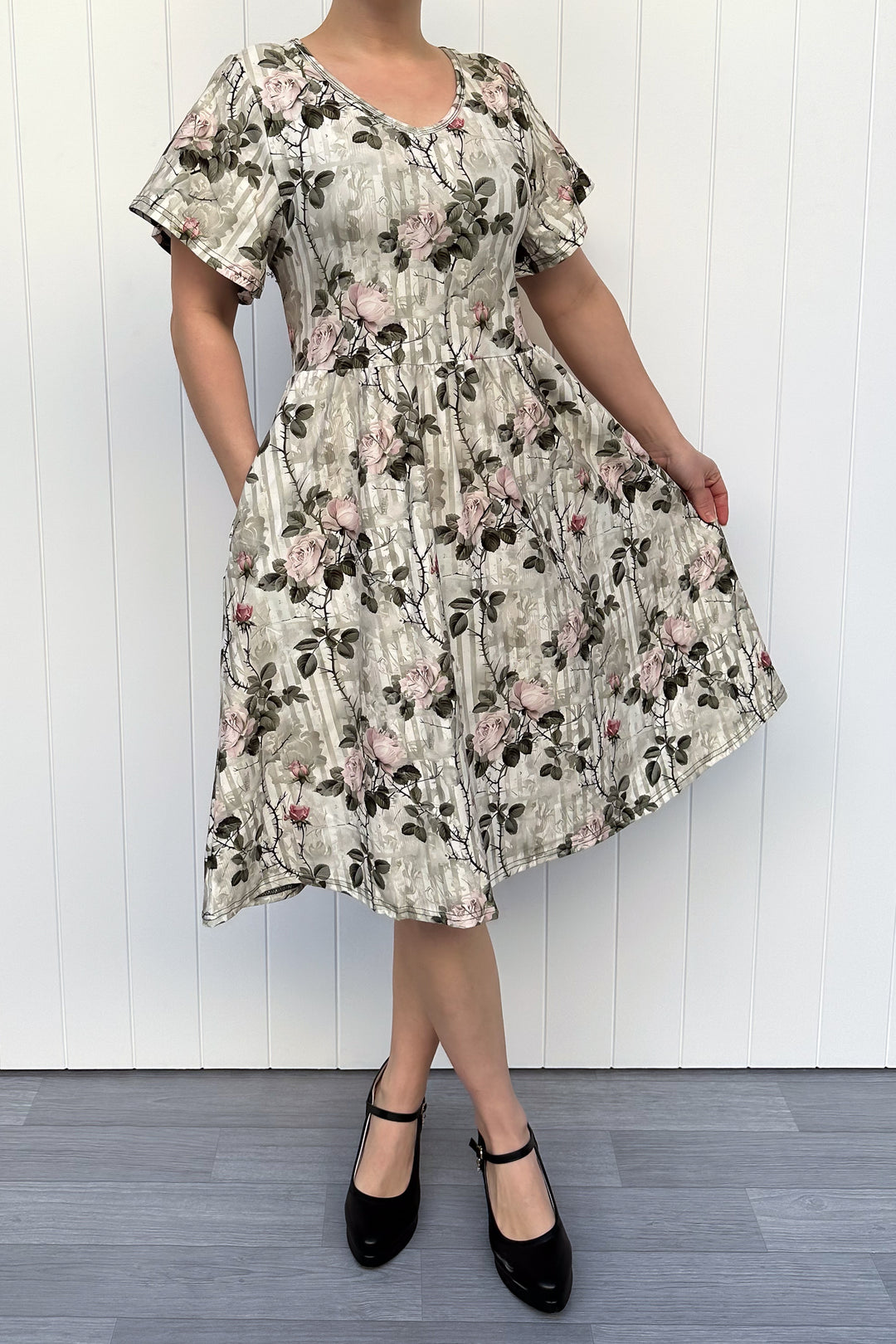 Woman wearing a floral dress against a white wooden panel background