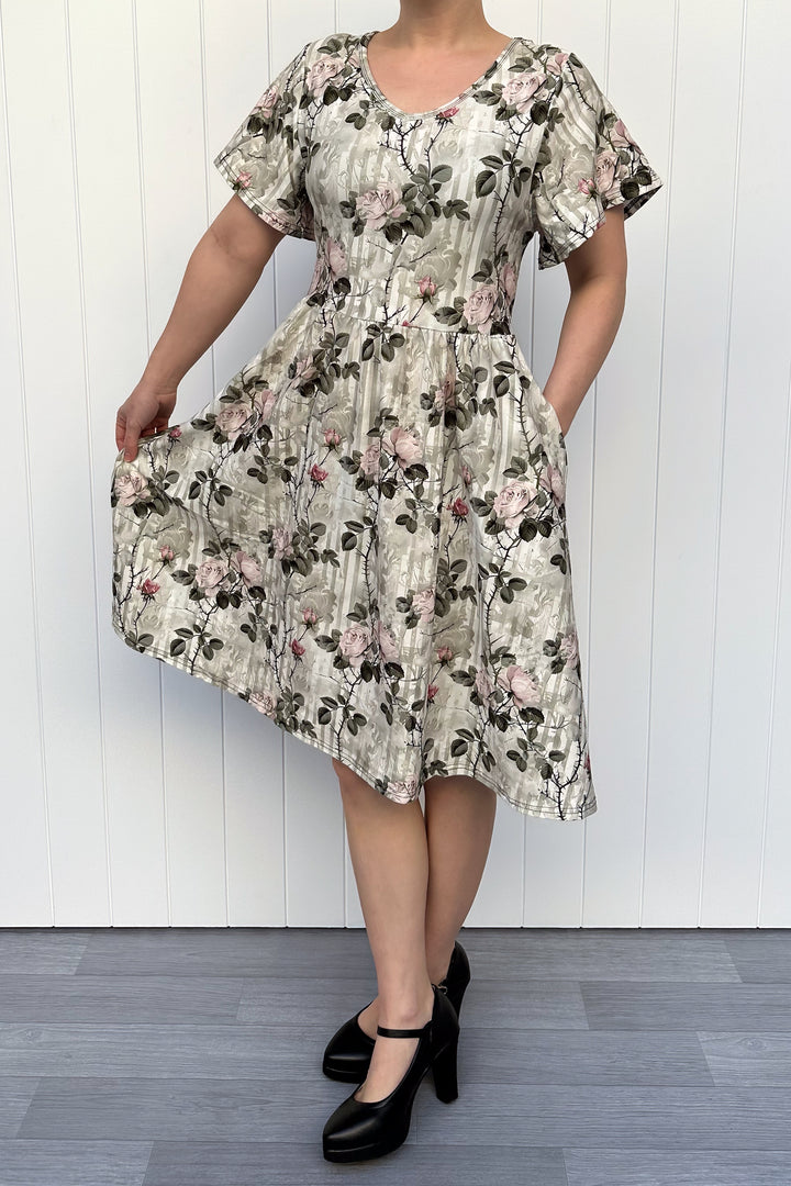Woman wearing a floral dress against a white wooden panel background