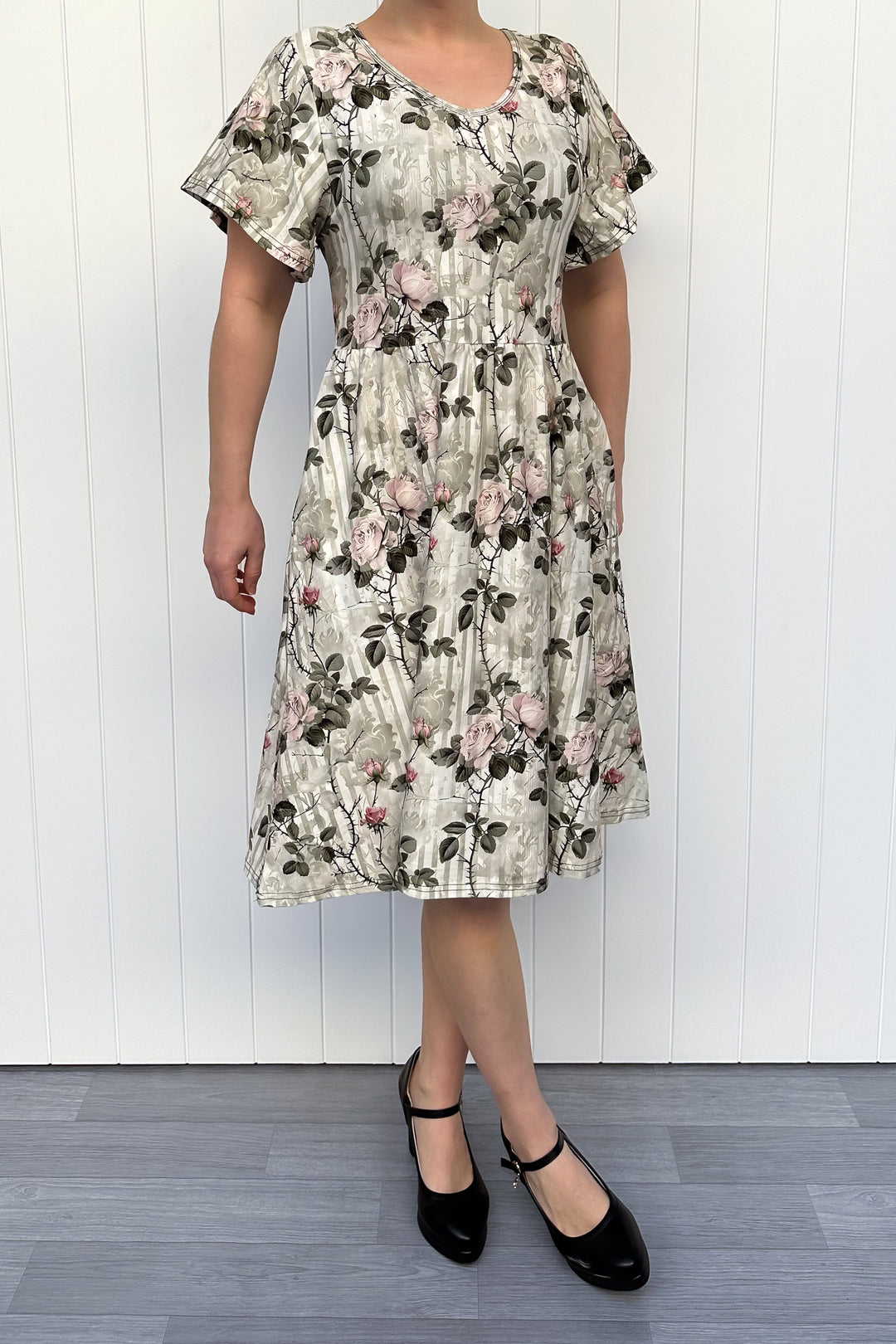 Woman wearing a floral dress against a white wooden panel background